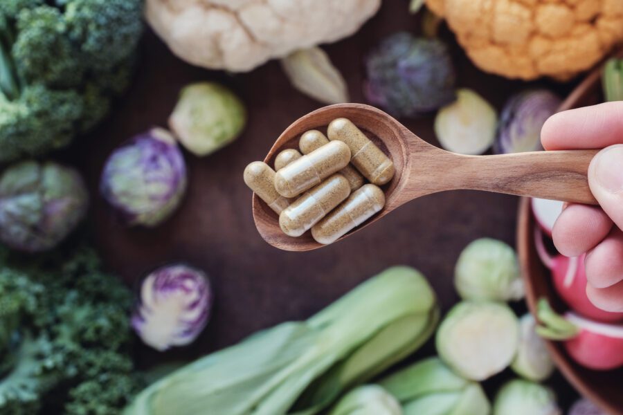 spoonful of supplements surrounded by vegetables